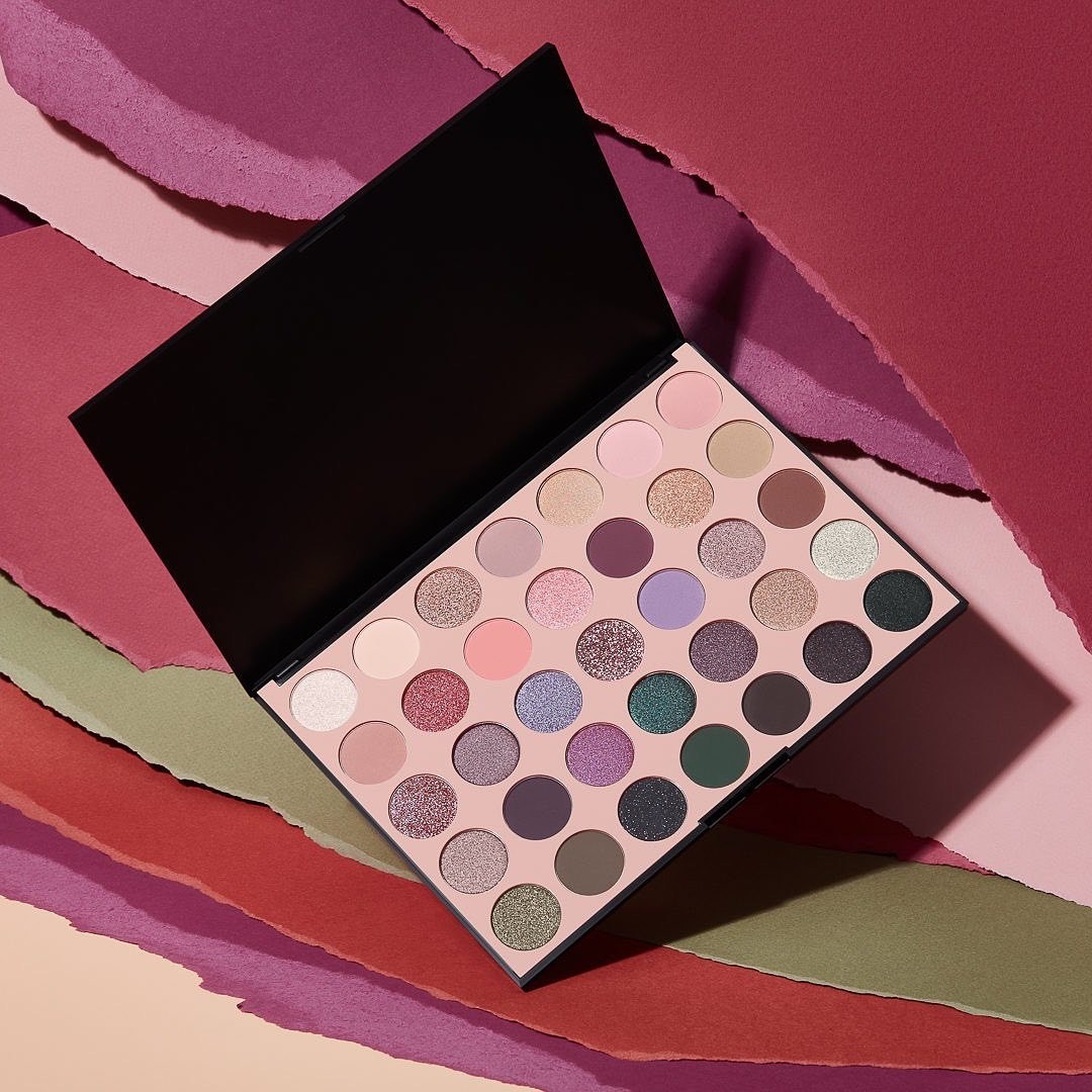 The eyeshadow palette open and perched on a background artfully constructed of torn paper
