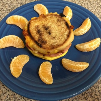 cooked english muffin breakfast sandwich with orange slices around it