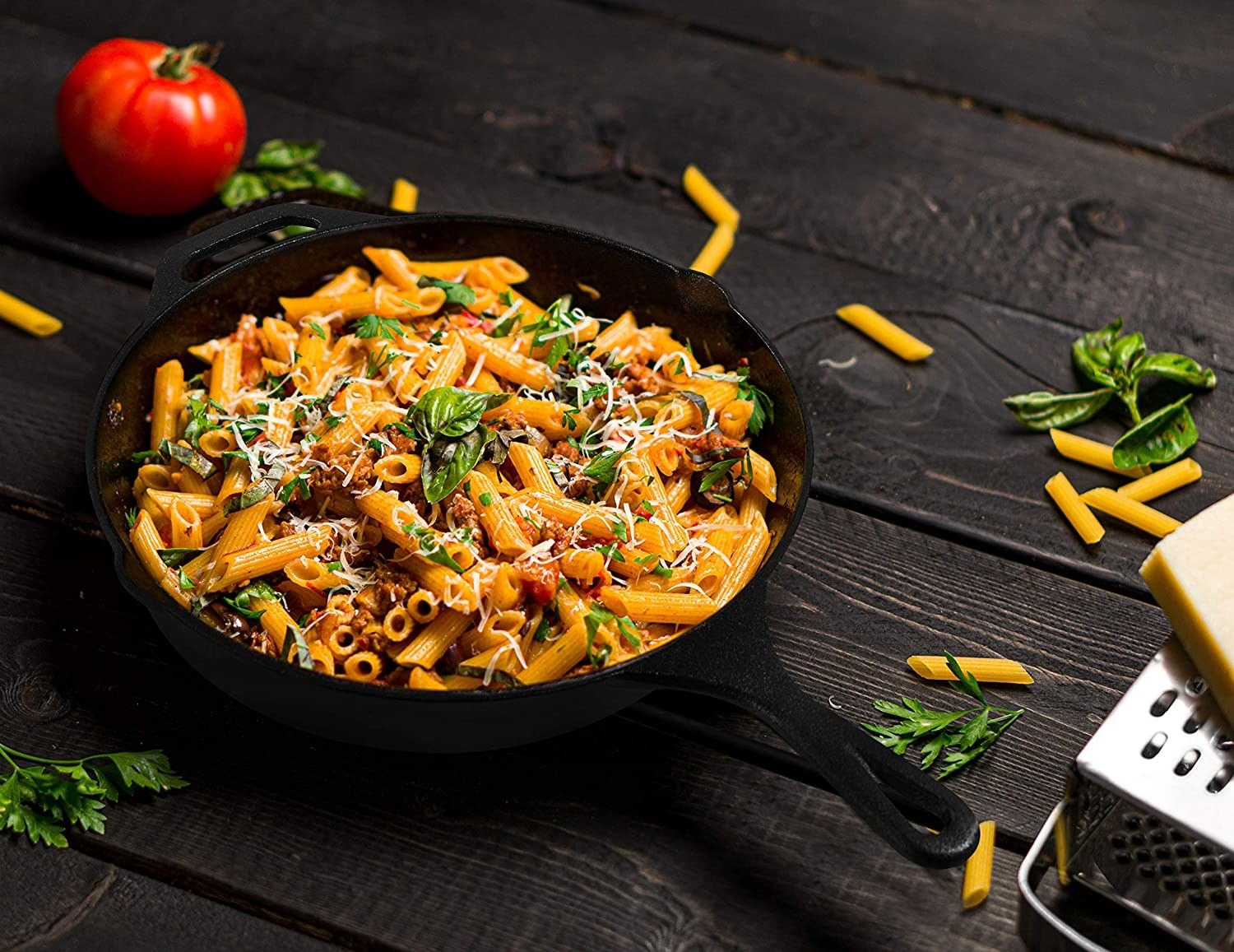 Penne with meat crumbles, tomato, basil, and cheese in a black cast-iron skillet