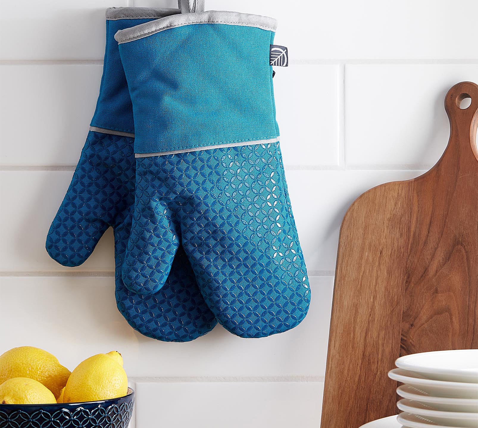A pair of oven mitts hanging from the wall