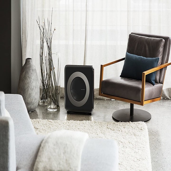 A black air purifier displayed in a modern looking living room