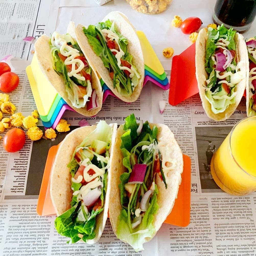 Red, orange, and yellow taco holders carrying soft shell tacos with all the fixings