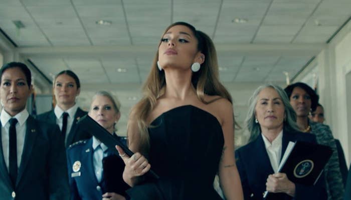 Ariana Grande walks in front of group of sharply dressed women in her music video &quot;Positions.&quot;