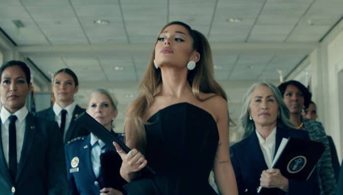 Ariana Grande walks in front of group of sharply dressed women in her music video "Positions."