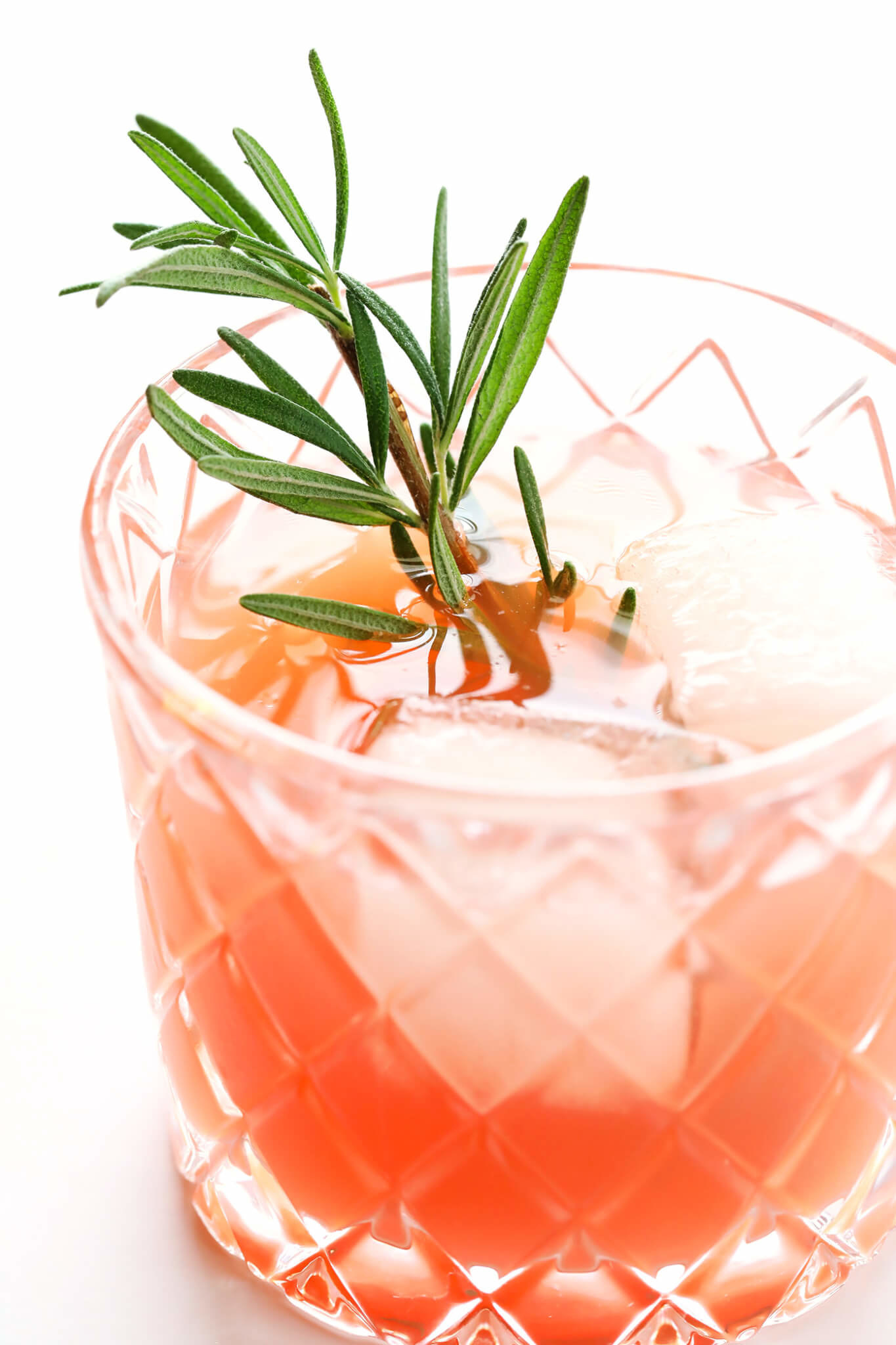 A grapefruit and elderflower gin cocktail garnished with rosemary. 