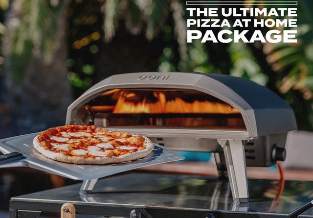 the dome shaped outdoor pizza oven with a pizza being slid into it