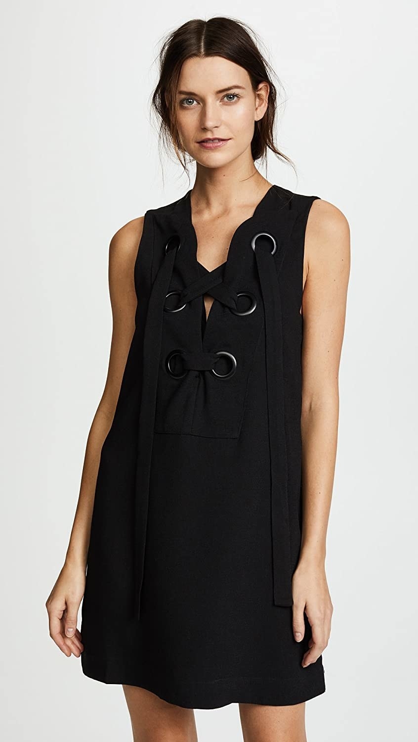 A model wearing the sleeveless dress with oversized sneaker-like lace-up detail at the neck in black