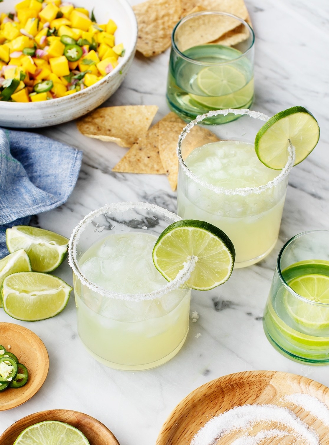 Two classic margaritas with lime wedges and salted rims.