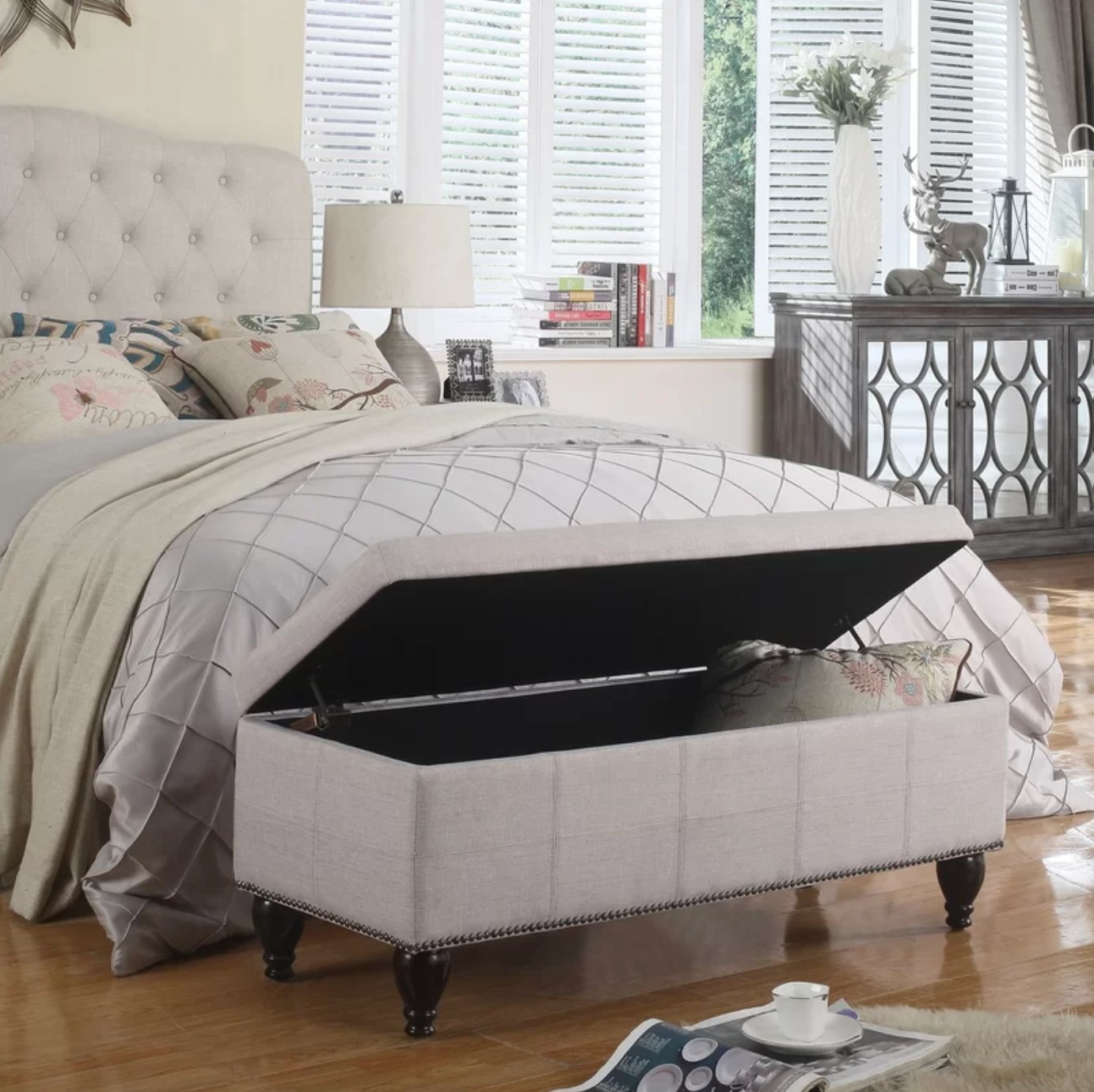 The upholstered storage bench in beige at the foot of a bed