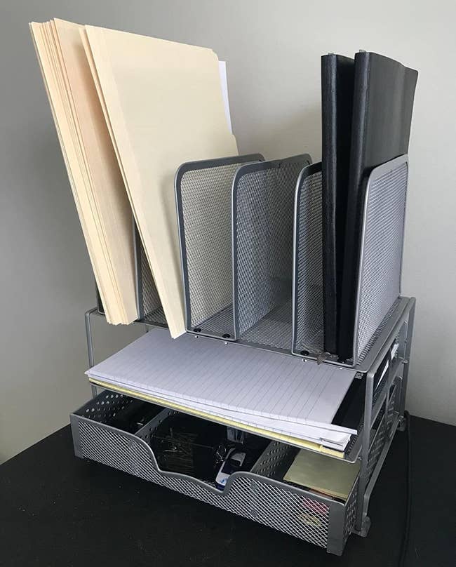 reviewer's mesh desk organizer holding sticky notes, folders, a stapler, notebook paper, and more 