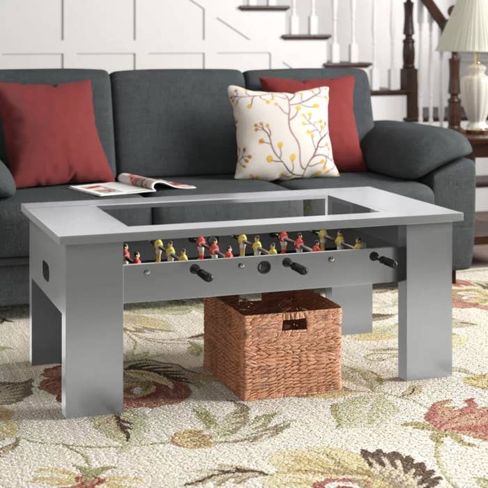 The foosball table in gray being used as a coffee table