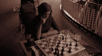 Beth moving a piece on the chess board
