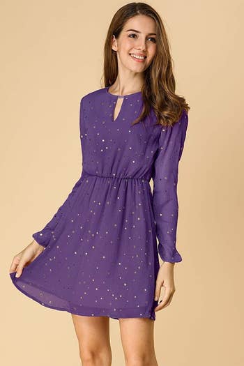 A model in the long-sleeved, keyhole-neckline dress in purple with gold stars