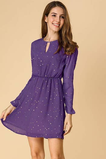A model in the long-sleeved, keyhole-neckline dress in purple with gold stars
