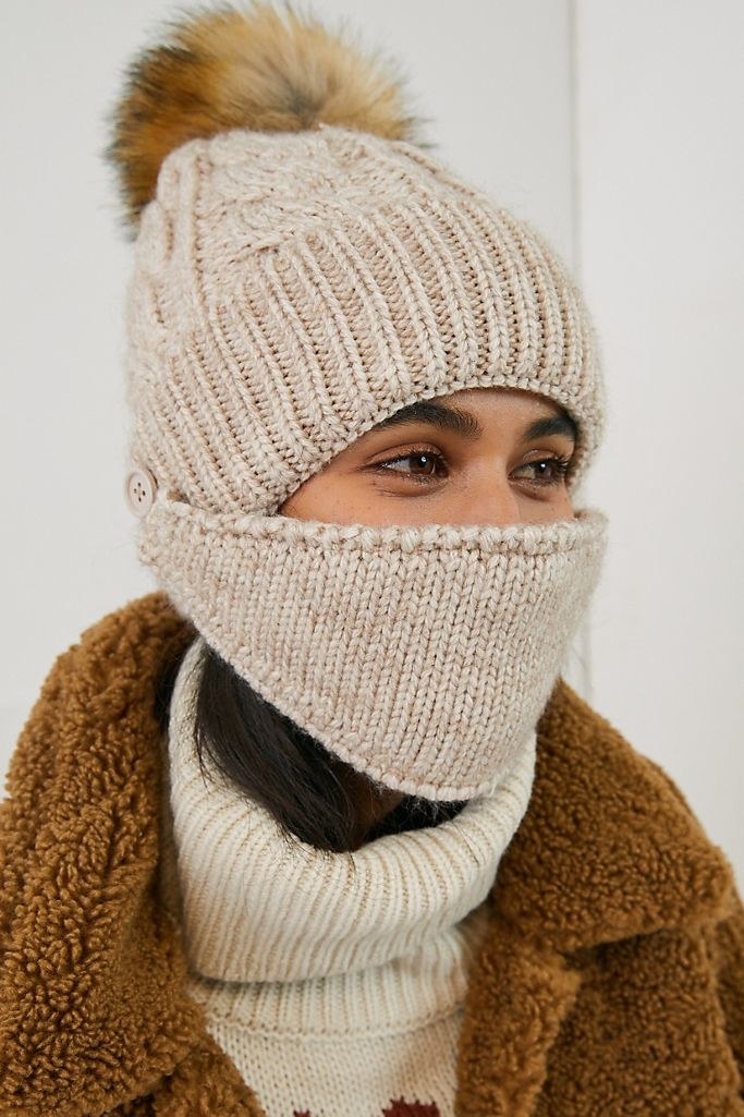 A model wearing the face mask and hat in ivory