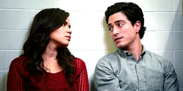 Jonah and Amy sitting against the wall looking at each other 