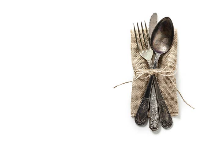 A place setting of silver with a burlap napkin all tied up with string