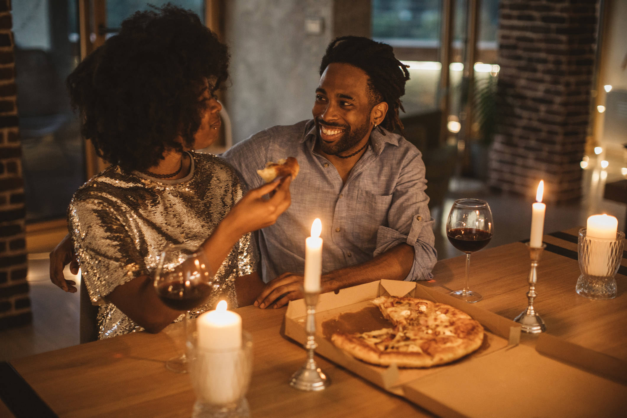A couple enjoying pizza by candlelight