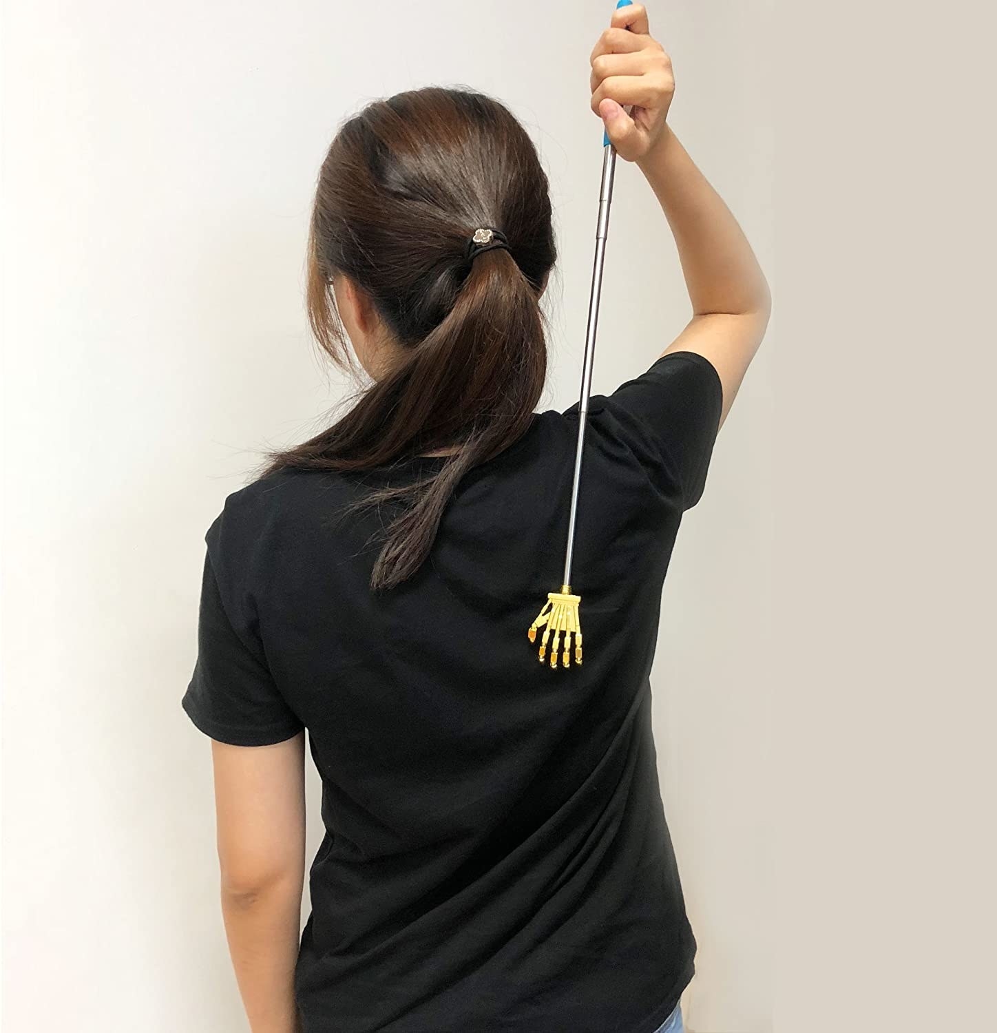 A person using the back scratcher while wearing a tee