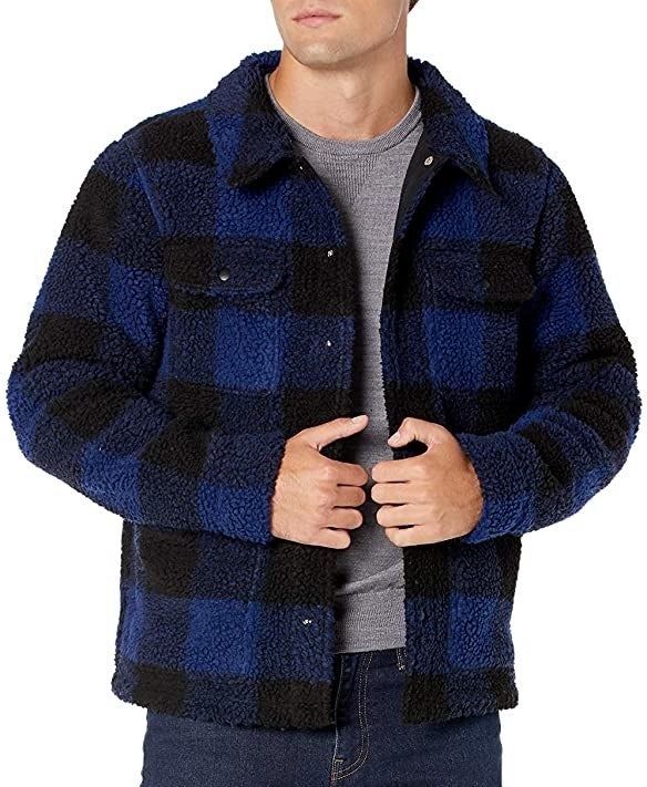 Model wearing the sherpa jacket in black and blue plaid with pockets on either side of the chest