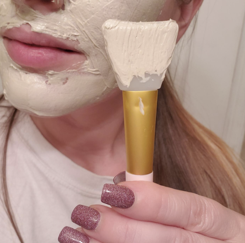 Reviewer photo of silicone mask brush next to face with mask applied using brush