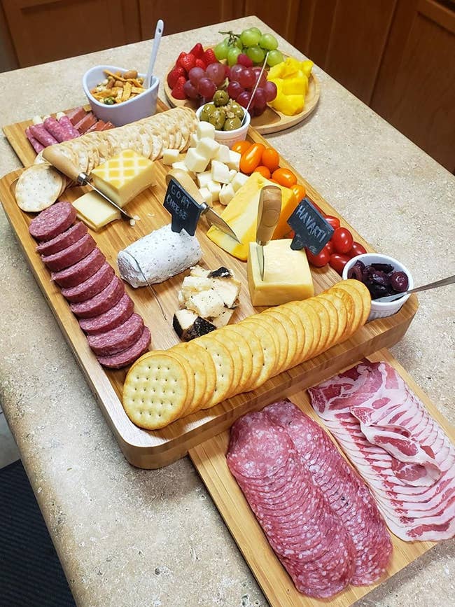 Reviewer picture of the wood board with drawers on either side open and the extra round plate next to it, all filled with food