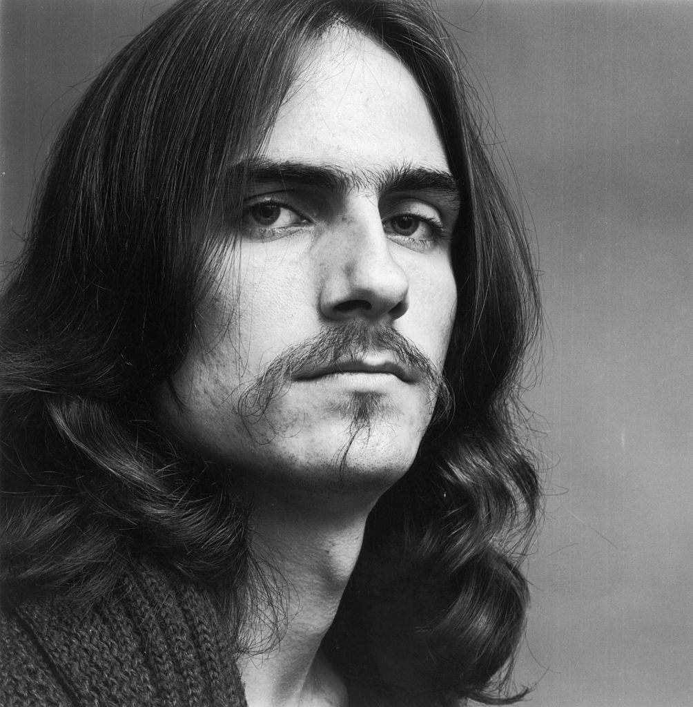 Headshot of James Taylor in 1969 with hair down to his shoulders and a mustache