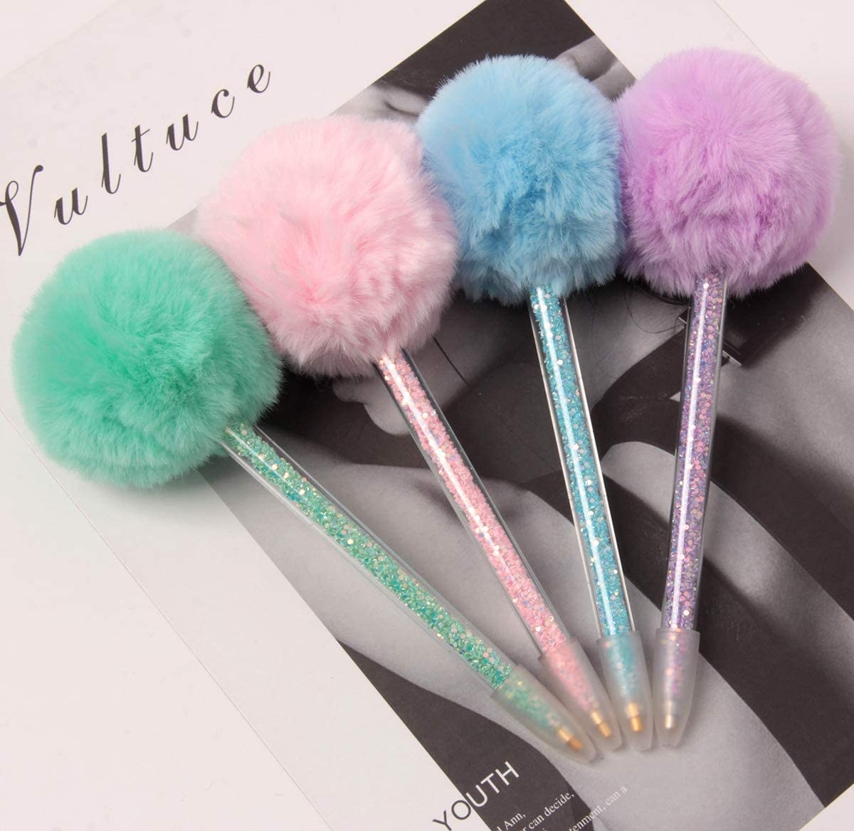 The pens in green, pink, blue, and purple with beads in the pens and a faux fur puff ball on top of each