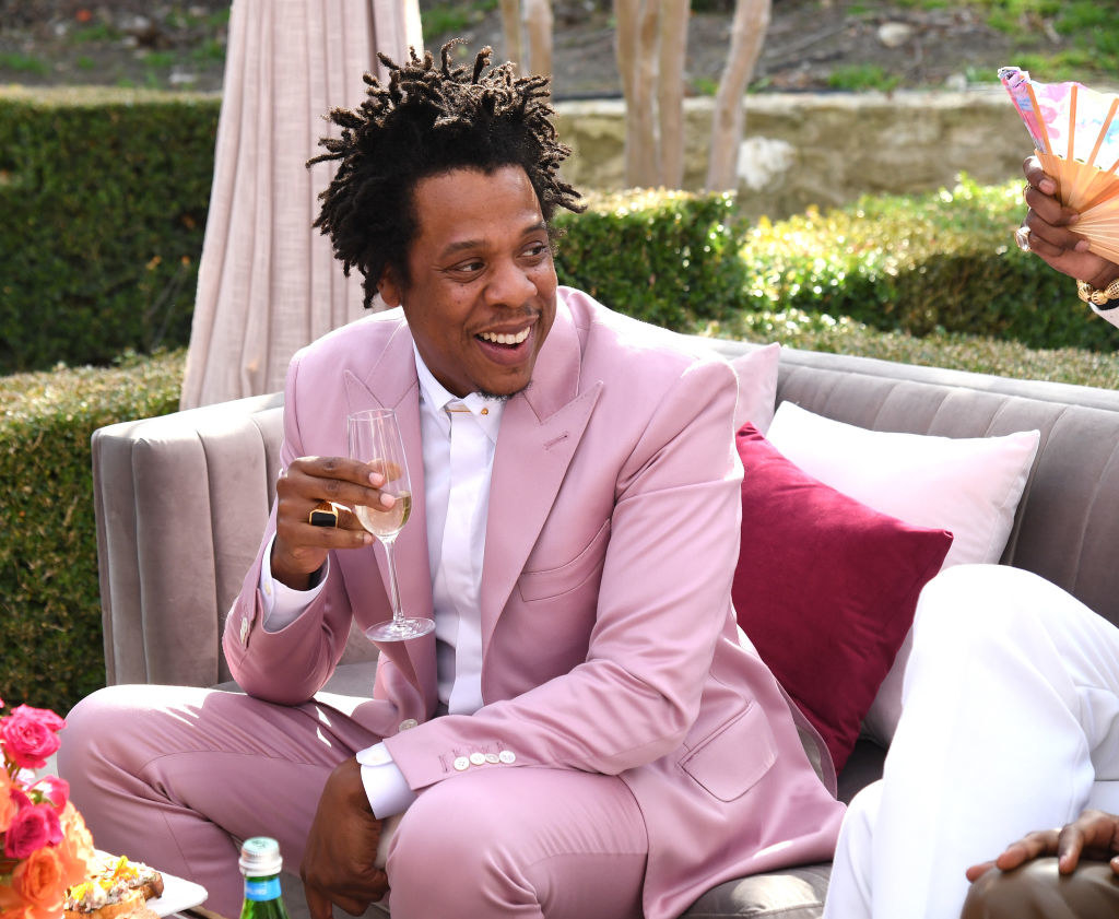 Jay-Z at the Roc Nation brunch, wearing a bright colored suit and drinking champagne
