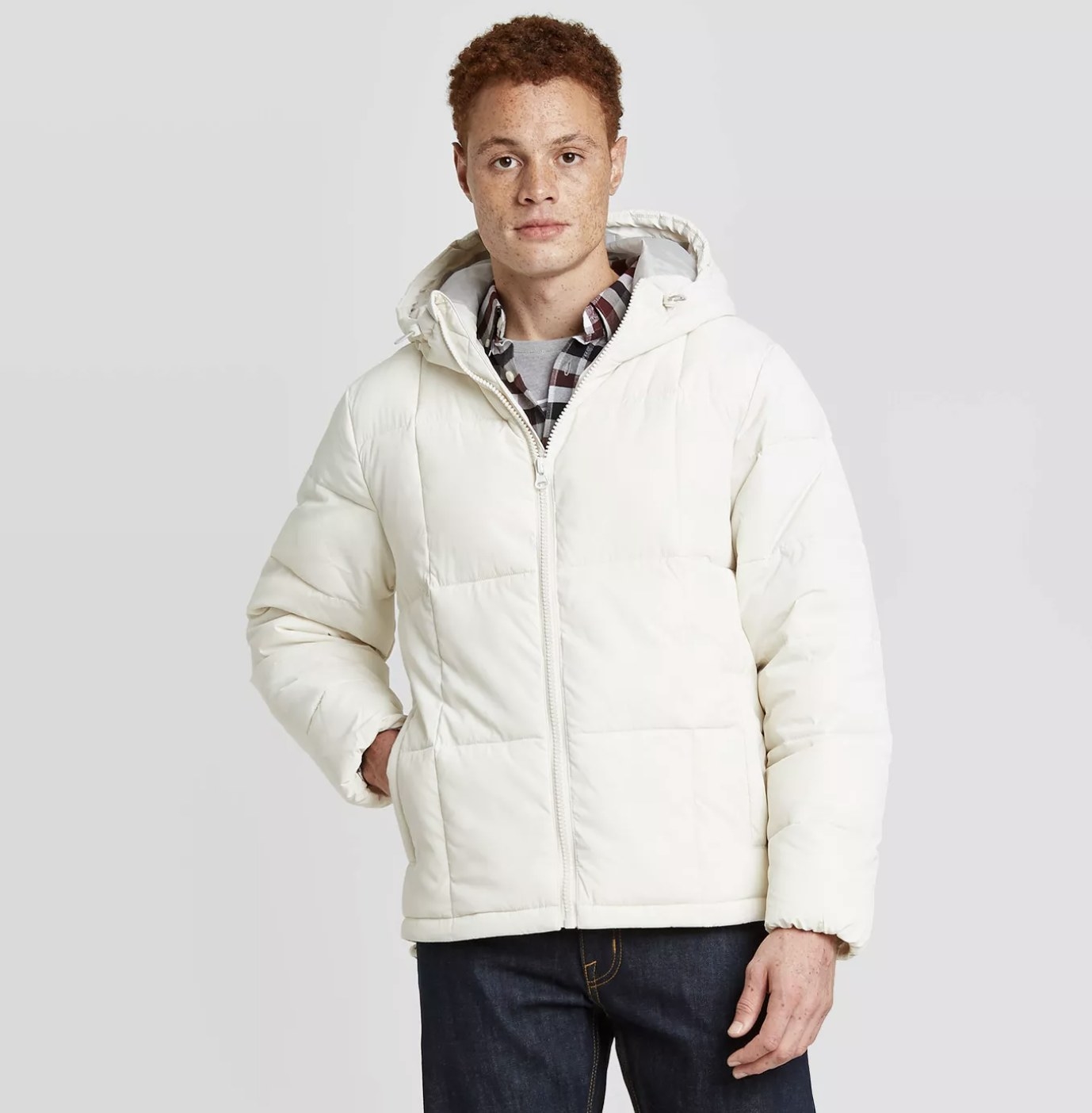 Model is wearing a white hooded puffer jacket and dark denim jeans