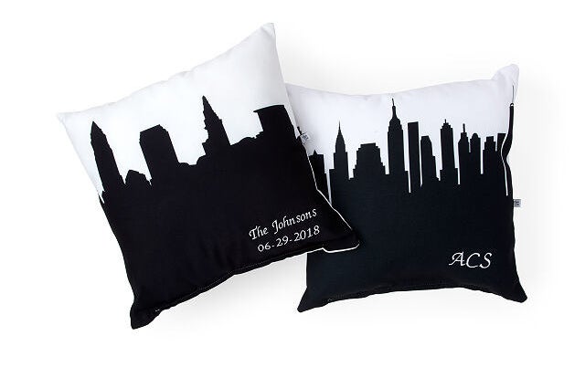 One white pillow with a black city skyline that says &quot;The Johnsons 06.29.2018&quot; in the corner and another pillow with a New York City skyline print that reads &quot;ACS&quot; in the corner