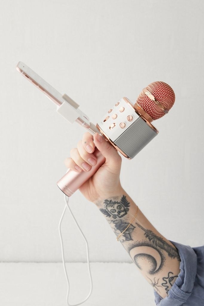 a model&#x27;s hand holding the rose gold karaoke microphone