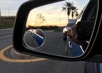The blind spot mirror attached to a rearview mirror showing more closely, how much room is next to the car door
