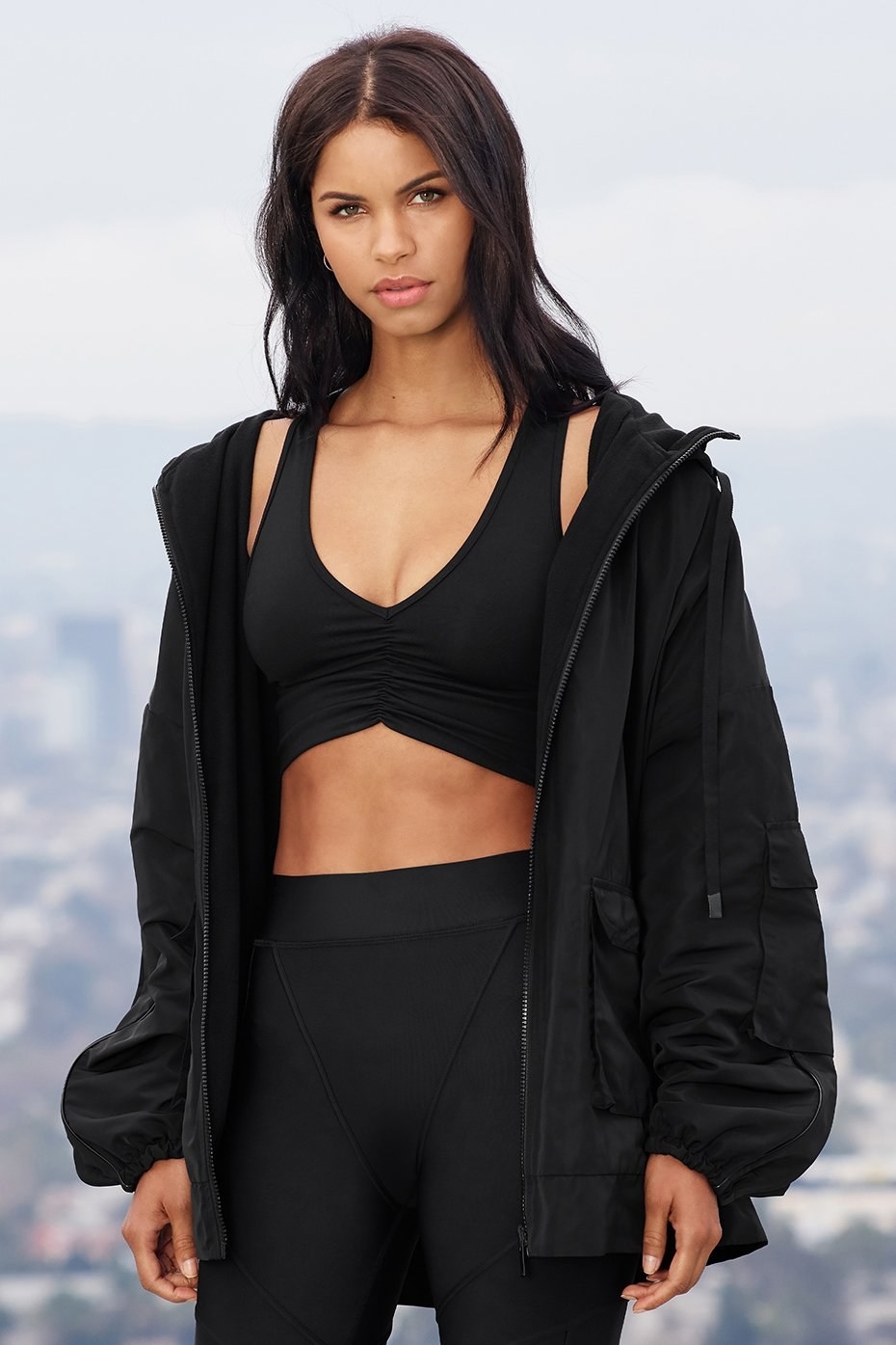 Model wears Alo Yoga reversible legion jacket in black