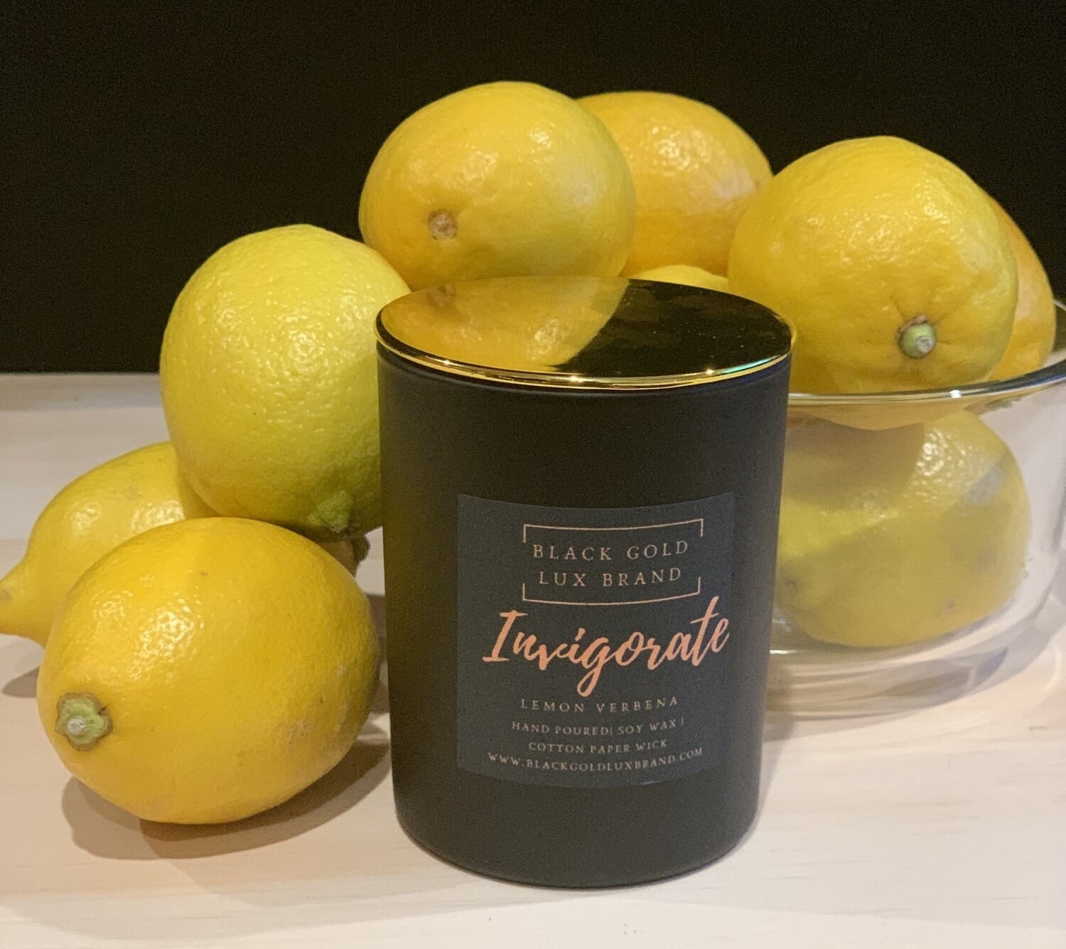 The Invigorate Candle surrounded by a bowl of lemons