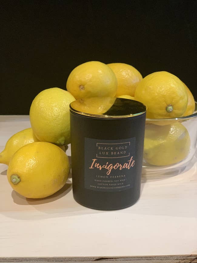The Invigorate Candle surrounded by a bowl of lemons