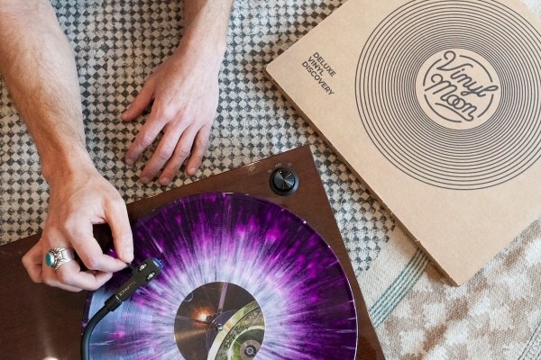 a hand putting a vinyl record on next to the Vinyl Moon box