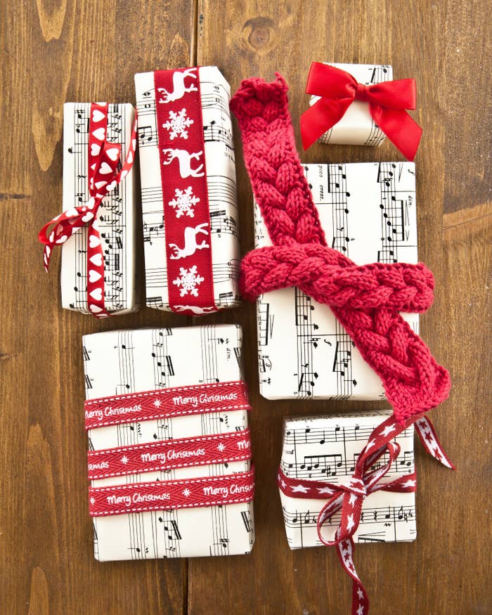 Multiple gifts wrapped in sheet music and red ribbon. 