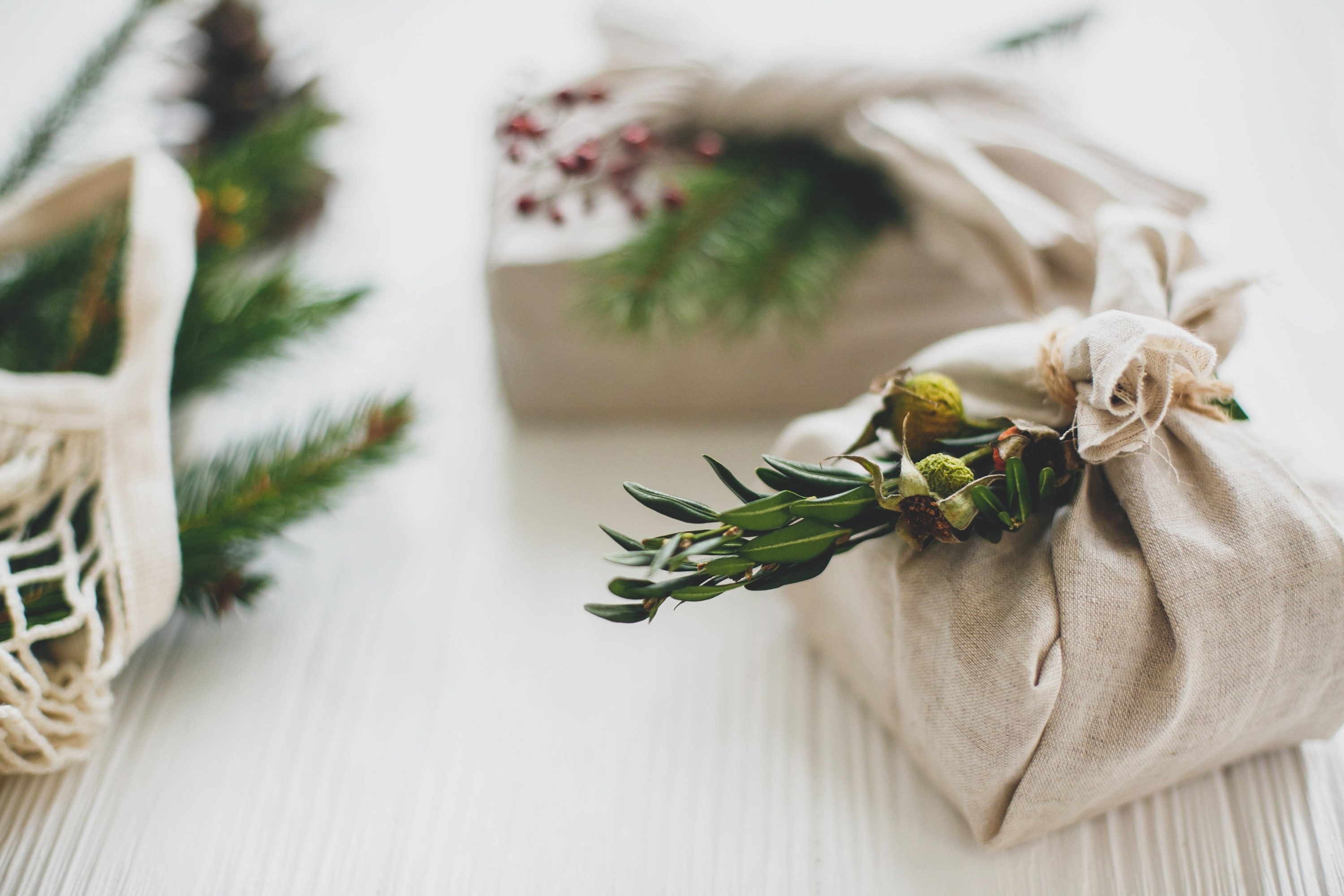 Multiple gifts wrapped in natural colored linen with fresh greenery. 