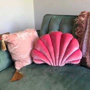 pink shell pillow on a green velvet couch