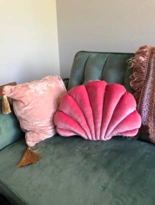 pink shell pillow on a green velvet couch