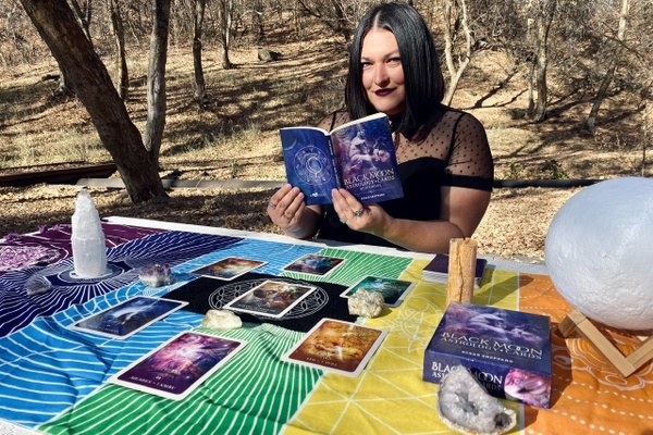 a person reading a book from the subscription with Tarot cards displayed in front of them 