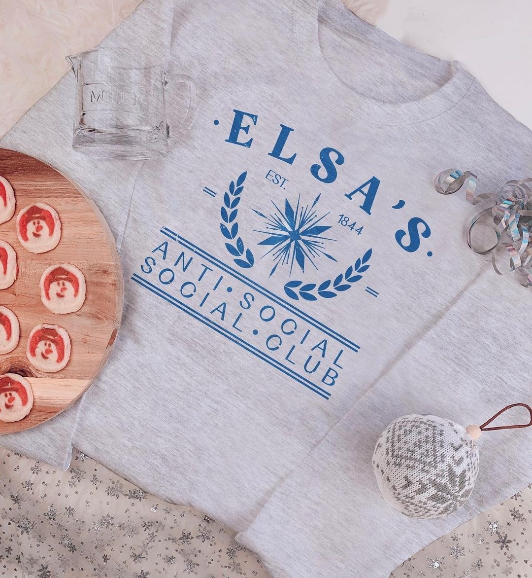 a gray sweatshirt with a snowflake on it and the word&#x27;s &quot;elsa&#x27;s anti social social club&quot;