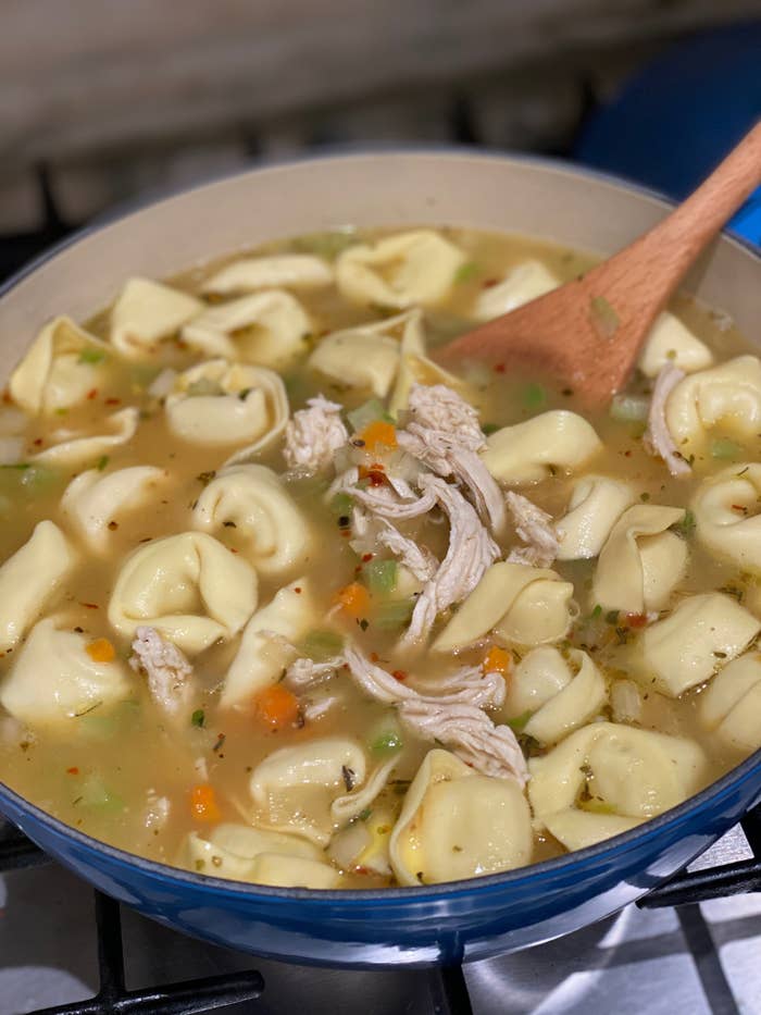 A pot of chicken tortellini soup with vegetables.