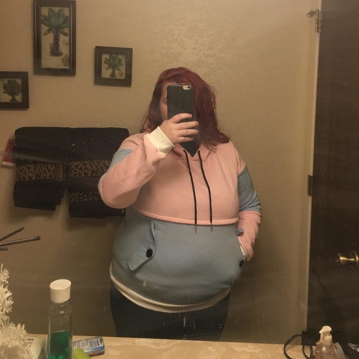 A reviewer wearing the hoodie in pink and blue