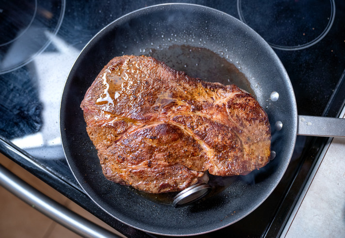 a steak cooking in a pan on the stove