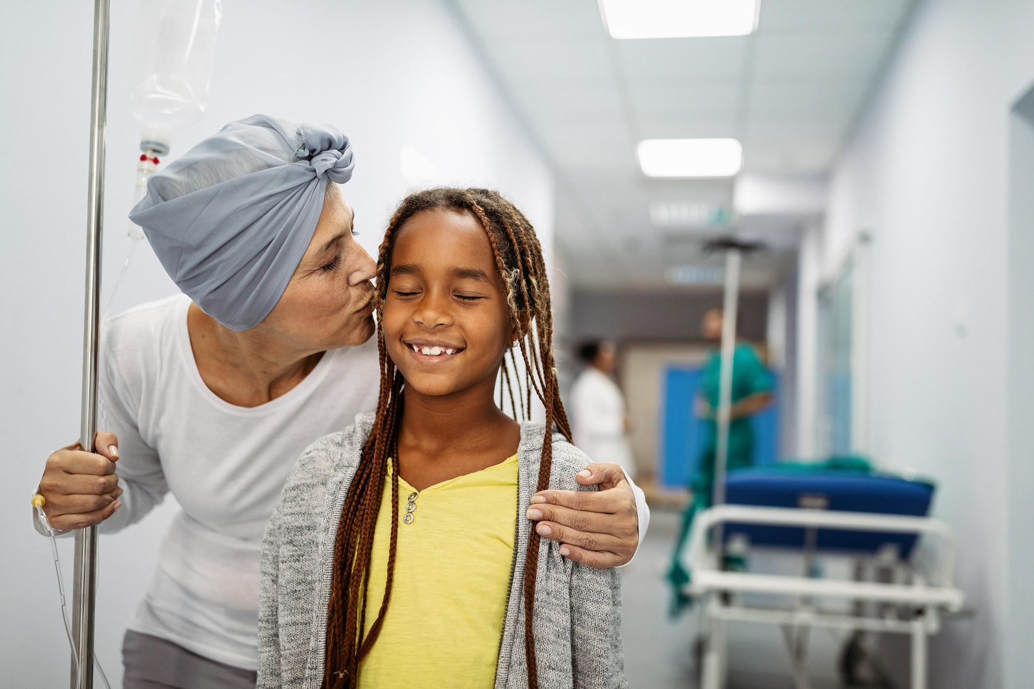 Sick senior woman with cancer hugging her young grandchild in hospital. Family support concept. 