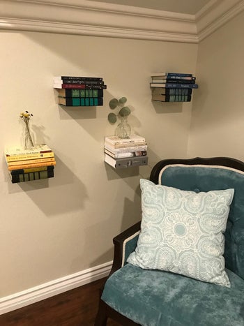 A customer review photo of their floating bookshelves on a wall next to a chair