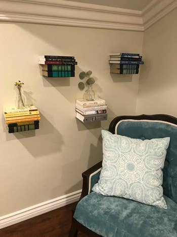 A customer review photo of their floating bookshelves on a wall next to a chair 