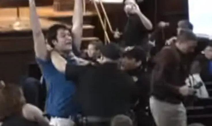 A man lifting his arms while being held down by cops 